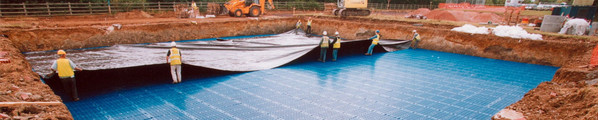 workers installing a huge roll of stormwater membrane